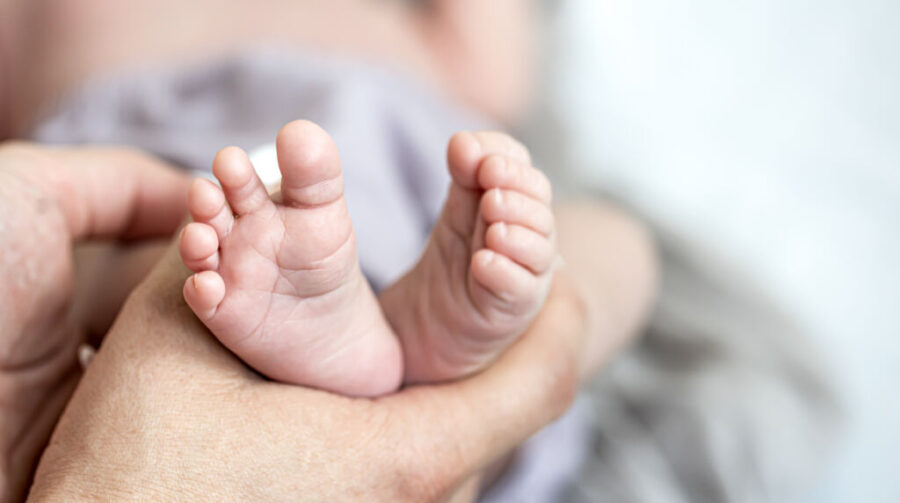Close-up of a mom holding the little feet of a newborn baby. Close up of a mom holding the little feet of a newborn baby.